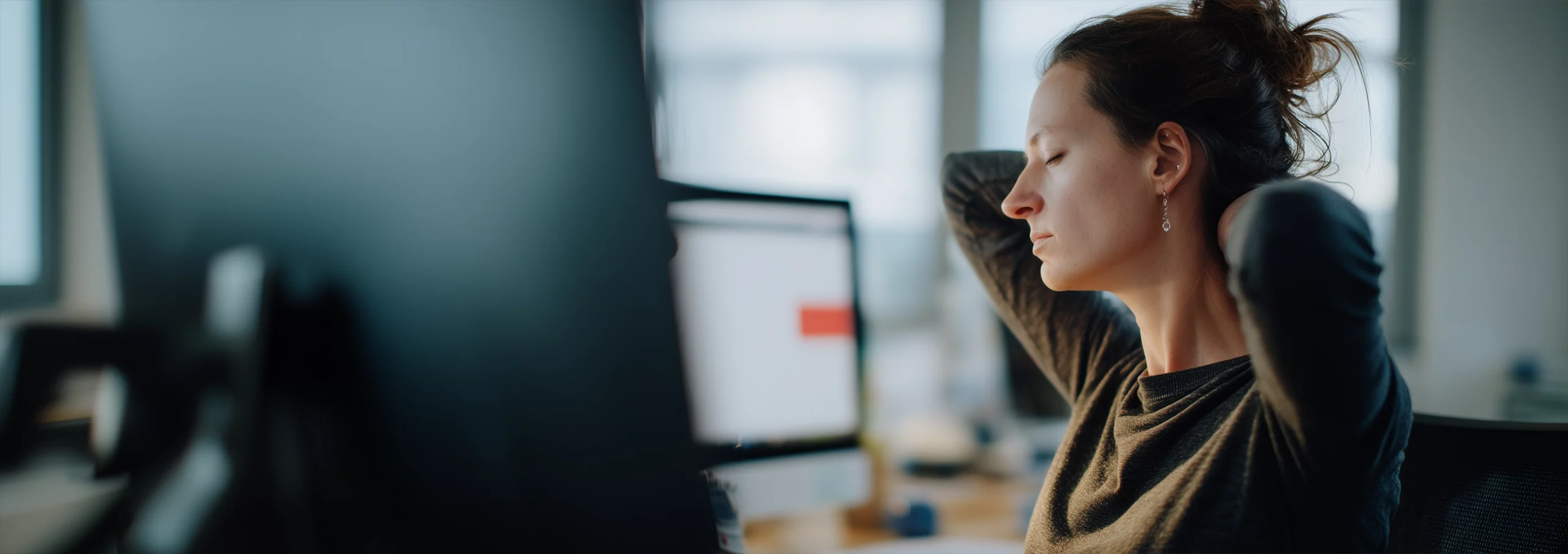 Salarié de bureau ressentant une tension à la nuque devant son poste de travail.